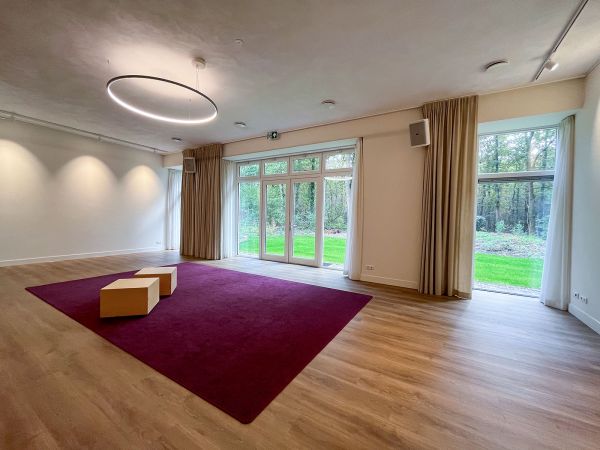 De prachtige zaal met uitzicht op het grasveld en bos